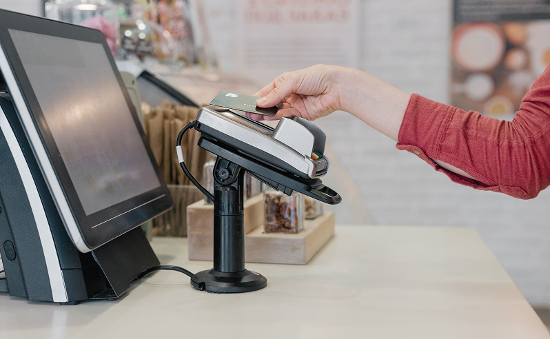 Klant houdt een betaalpas tegen een betaalterminal voor contactloos betalen bij de kassa.
