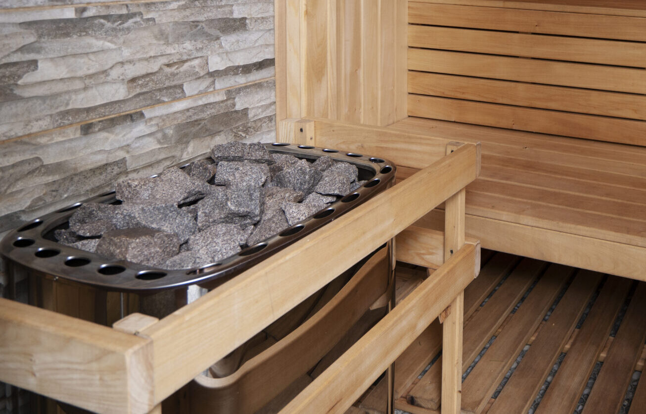 Houten sauna met stenen op kachel.